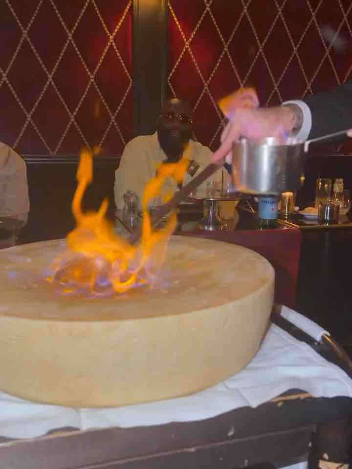 Rick Ross in Paris, France, watching his food get cooked on a Parmesan cheese wheel